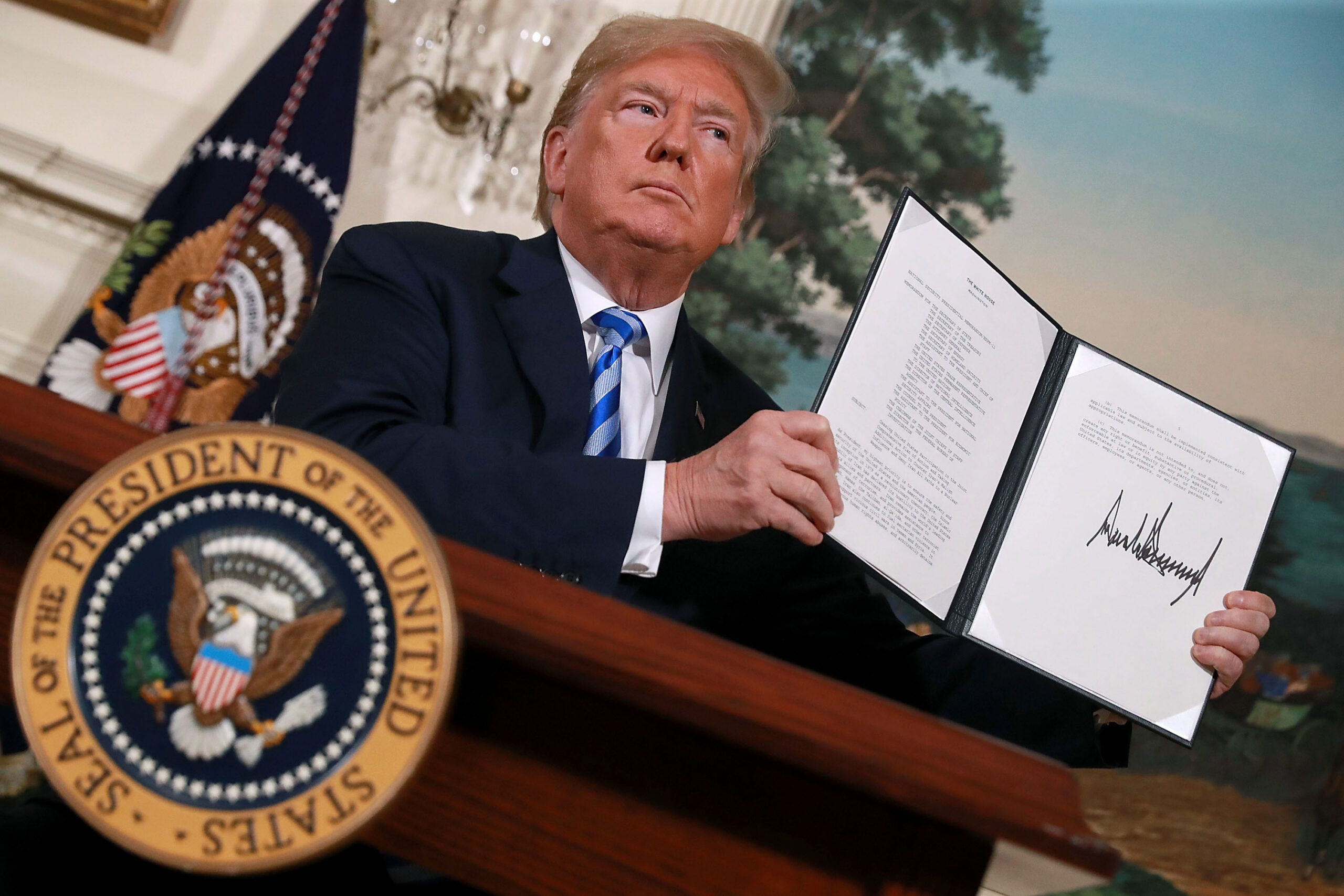 WASHINGTON, DC - MAY 08: U.S. President Donald Trump holds up a memorandum that reinstates sanctions on Iran after he announced his decision to withdraw the United States from the 2015 Iran nuclear deal in the Diplomatic Room at the White House May 8, 2018 in Washington, DC. After two and a half years of negotiations, Iran agreed in 2015 to end its nuclear program in exchange for Western countries, including the United States, lifting decades of economic sanctions. Since then international inspectors have n