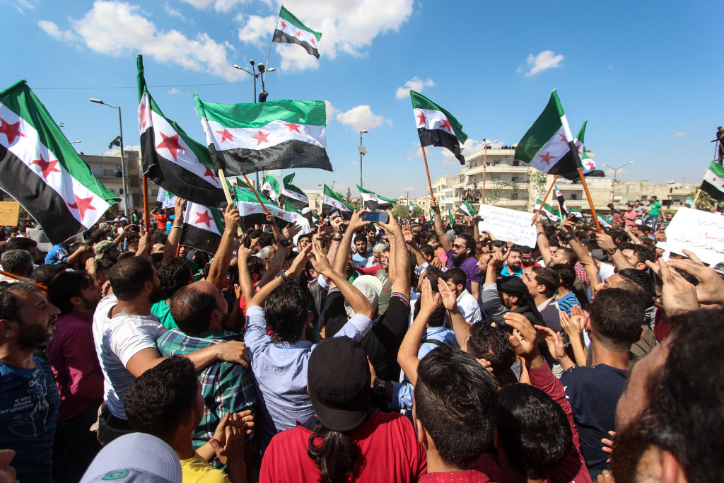  People seen waving flags during the protest against the Syrian regime in Idlib in September 2018.