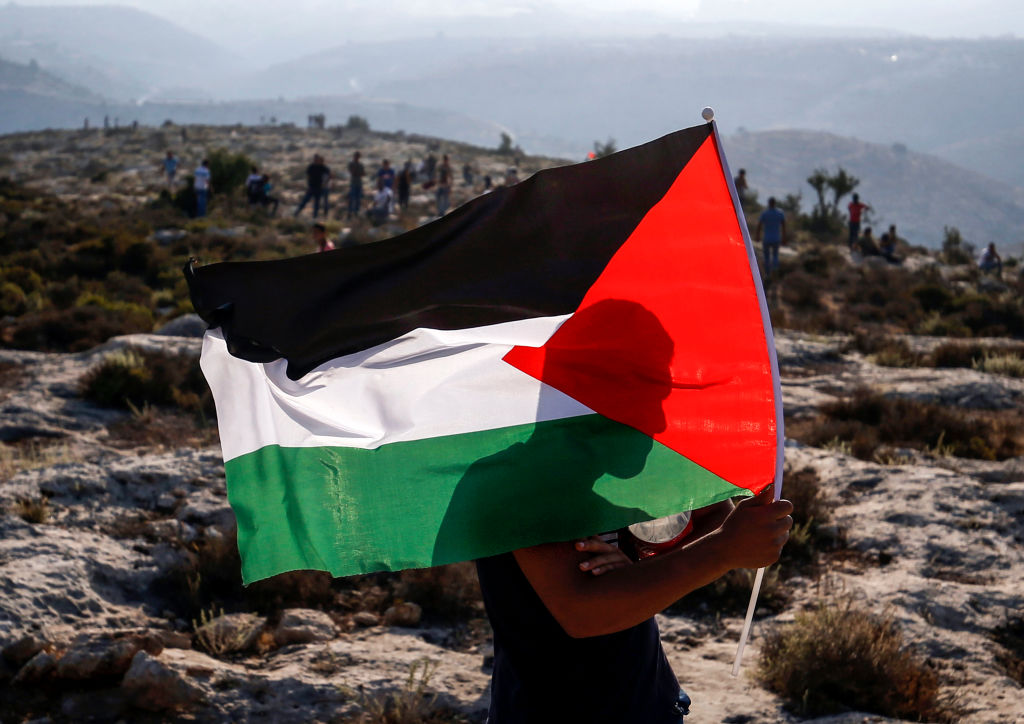 A Palestinian protester waves a Palestinian flag during a demonstration in the village of Ras Karkar west of Ramallah in the occupied West Bank on September 4, 2018. 