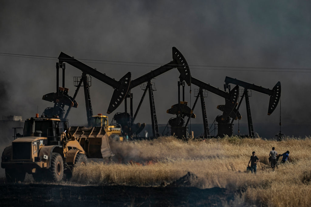 People battle a blaze next to an oil well in an agricultural field in the town of al-Qahtaniyah, in the Hasakeh province near the Syrian-Turkish border on June 10, 2019.