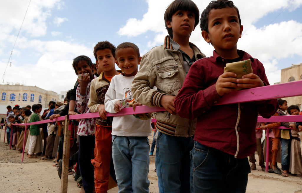 Yemeni children queue to obtain dinner meal distributed as aids by a local charity, the Amalona organization, on May 18, 2019 in Sana’a, Yemen. 