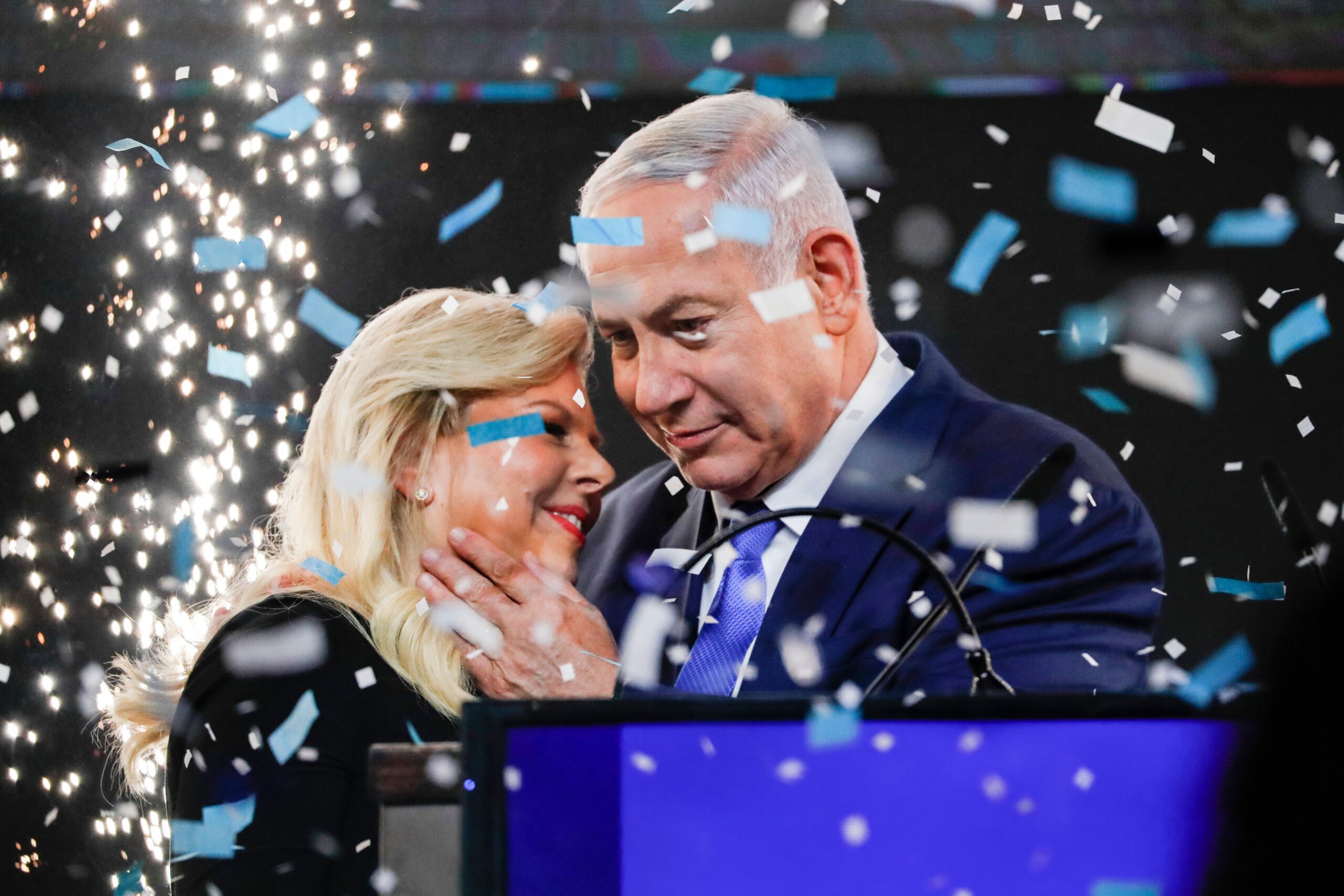 TOPSHOT - Israeli Prime Minister Benjamin Netanyahu embraces his wife Sara as confetti and fireworks are blown during his appearance before supporters at his Likud Party headquarters in the Israeli coastal city of Tel Aviv on election night early on April 10, 2019. (Photo by Thomas COEX / AFP) (Photo credit should read THOMAS COEX/AFP/Getty Images)