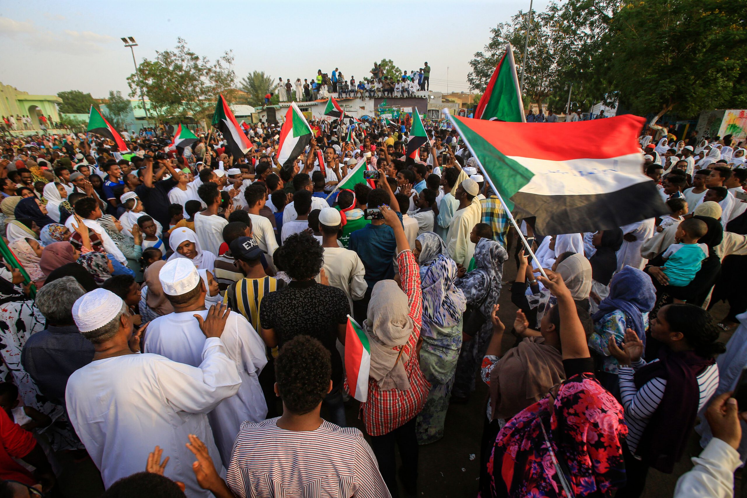 Sudanese people chant slogans and wave national flags as they celebrate after protest leaders struck a deal with the ruling generals on a new governing body, in the capital Khartoum's eastern district of Burri on July 5, 2019, - The deal, reached in the early hours of July 5 after two days of hard-won talks brokered by Ethiopian and African Union mediators, provides for the interim governing body to have a rotating presidency, as a compromise between the positions of the generals and the protesters. The blu