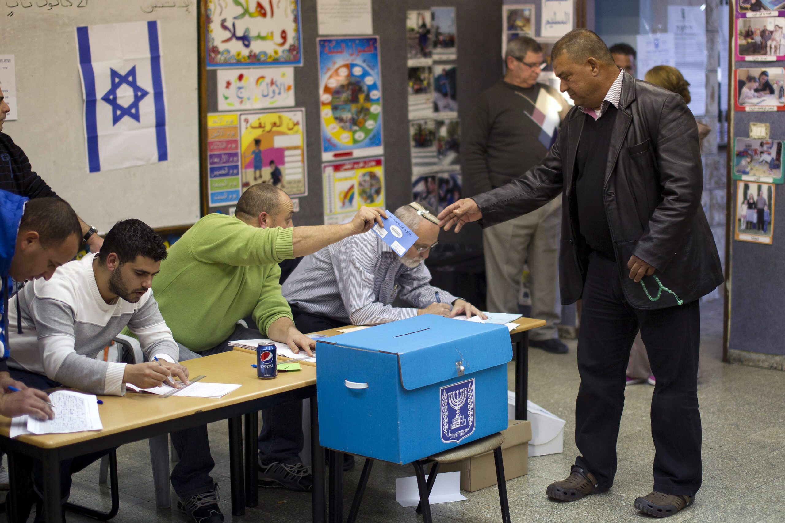 An Arab-Israeli man takes a ballot from a polling station official as he arrives to vote in the northern Arab-Israeli town of Sakhnin on January 22, 2013. 