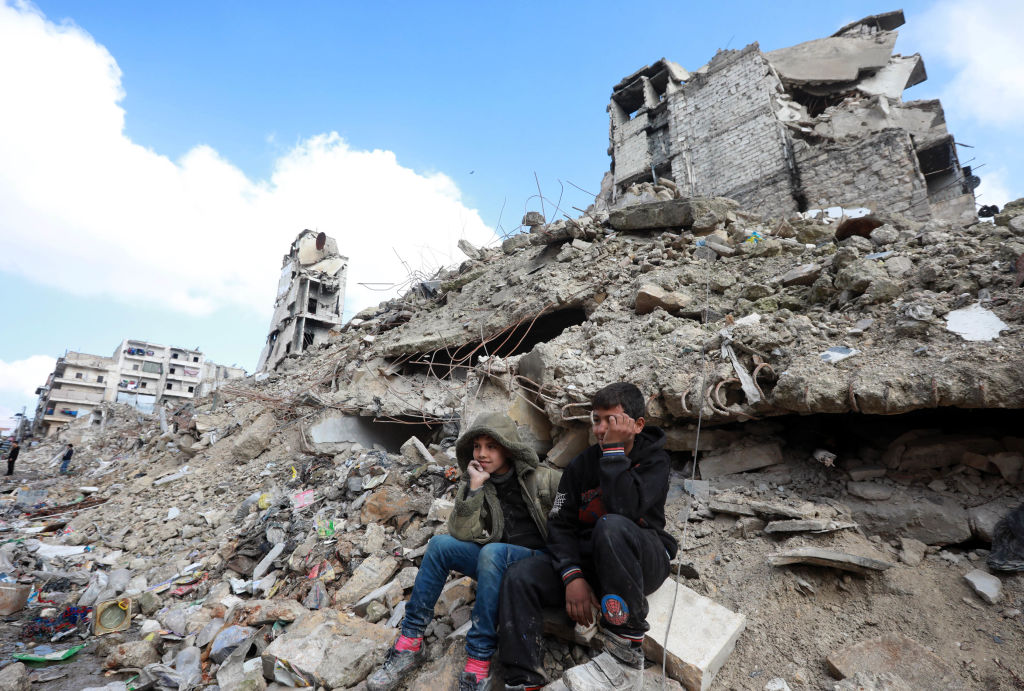 Children sit on the rubble of buildings in Aleppo, Syria.