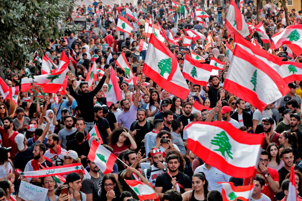 Lebanese protesters wave national flags during demonstrations to demand better living conditions and the ouster of a cast of politicians who have monopolised power and influence for decades, on October 21, 2019 in downtown Beirut. 
