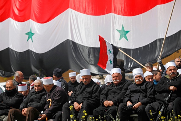 Druze residents of the Israeli-annexed Golan Heights gather under a huge Syrian national flag during a rally held in the Druze village of Majdal Shams on April 17, 2019 to mark Syria's Independence Day.