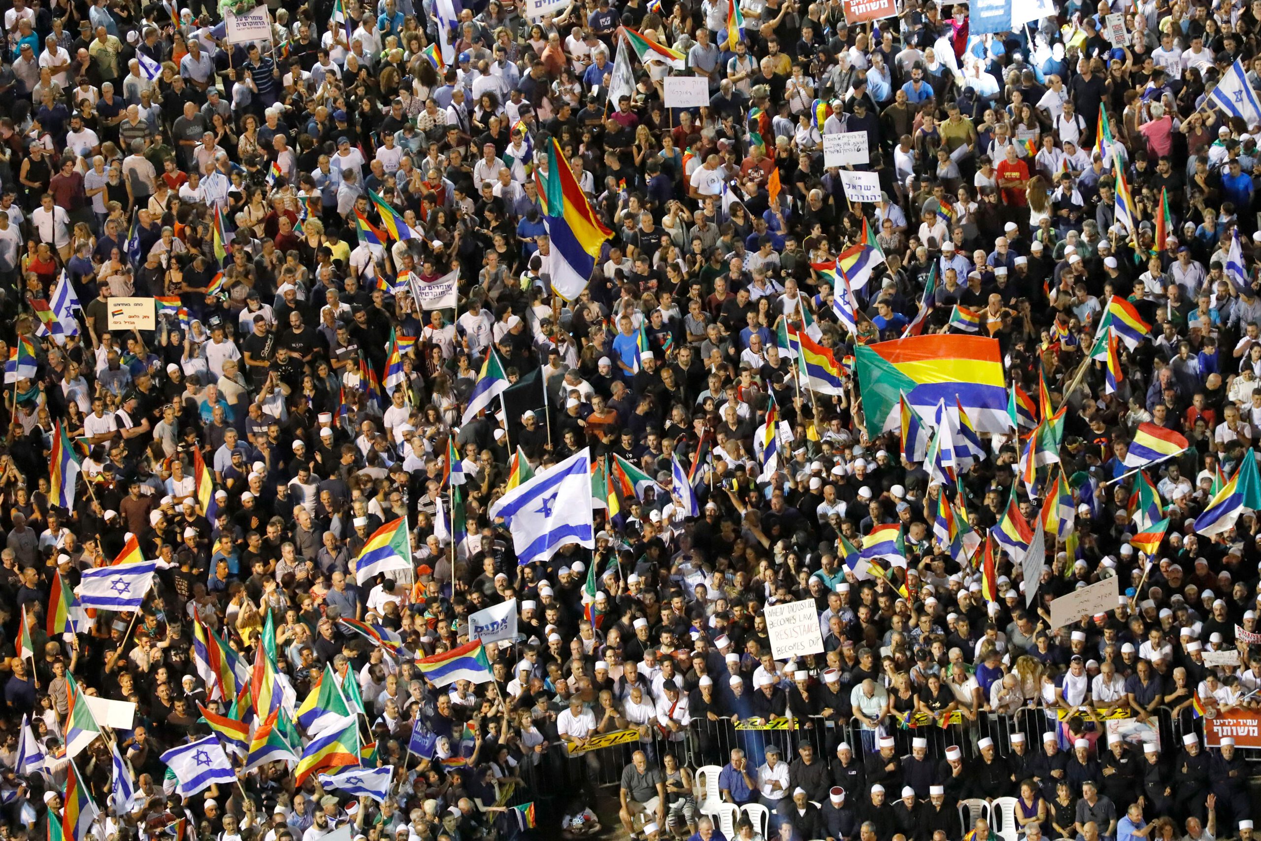 Members of the Israeli Druze community and their supporters wave their flags as they demonstrate during a rally to protest against the 'Jewish Nation-State Law' in the Israeli coastal city of Tel Aviv on August 4, 2018.