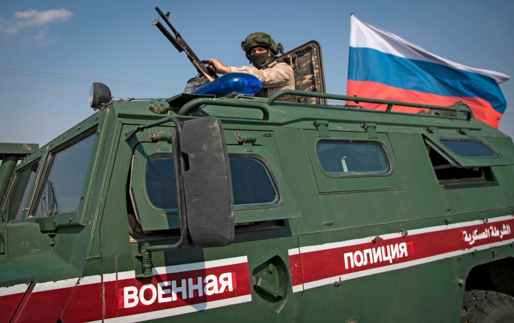 A soldier rides atop a Russian military vehicle near the Syrian northeastern city of Qamishli on October 26, 2019. 