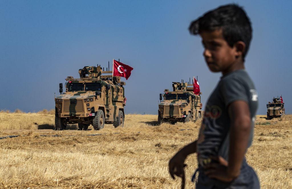 A Syrian boy watches as Turkish military vehicles, part of a US military convoy, take part in joint patrol in the Syrian village of al-Hashisha on the outskirts of Tal Abyad town along the border with Turkey, on October 4, 2019. 