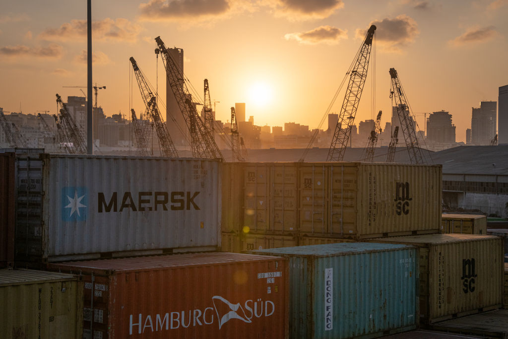 The sun sets behind the urban skyline as port cranes and shipping containers sit in an industrial transport area in Beirut, Lebanon, on 11 October 2019. 