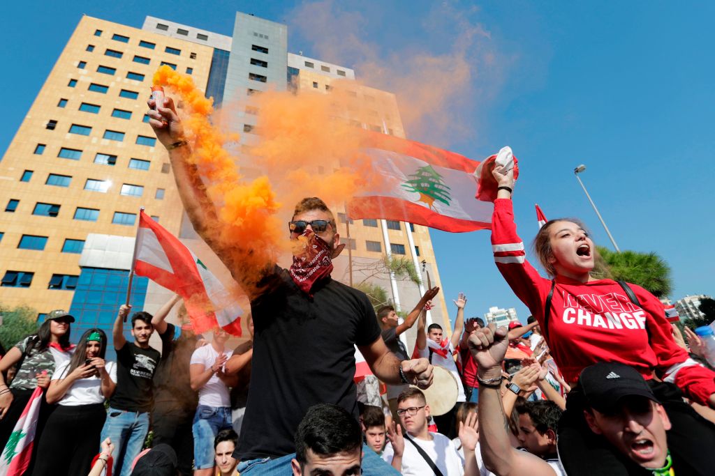 Lebanese students wave the national flag and chant slogans as they gather outside the Ministry of Education and Higher Education during ongoing anti-government protests, in the capital Beirut on November 8, 2019.
