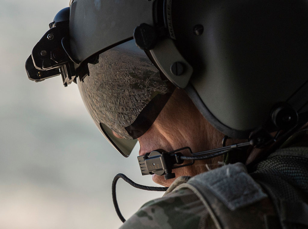 A partial view of the Iraqi capital Baghdad is reflected in the visor of a US Army helicopter crew member as he looks out of a Chinook helicopter flying from the US Embassy to Baghdad International airport, following the helicopter of US secretary of State Mike Pompeo, on January 9, 2019. 