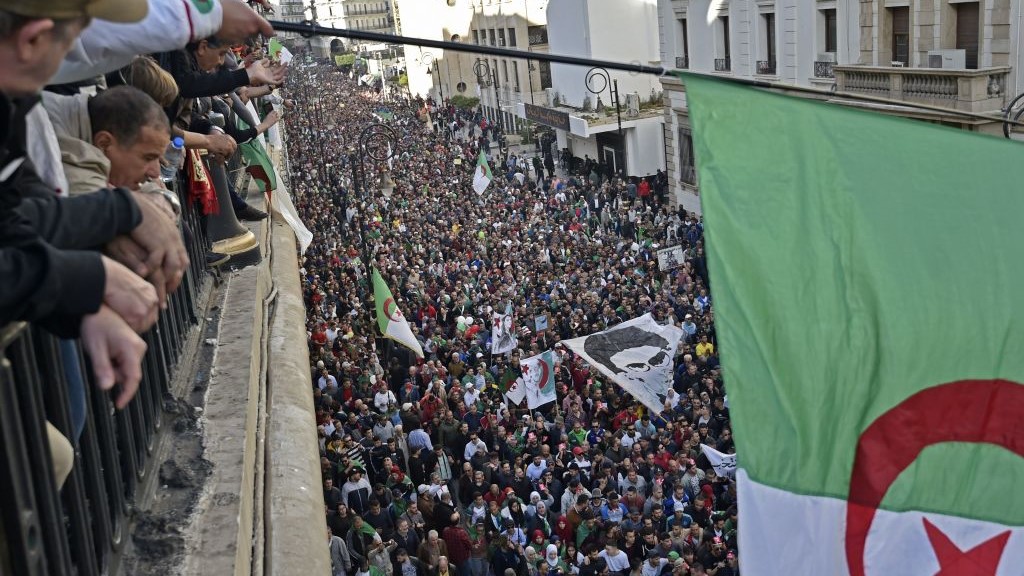  Algerians wave a national flag from a balcony as they watch anti-government demonstrators march in the capital Algiers on December 6, 2019, ahead of the presidential vote scheduled for December 12.