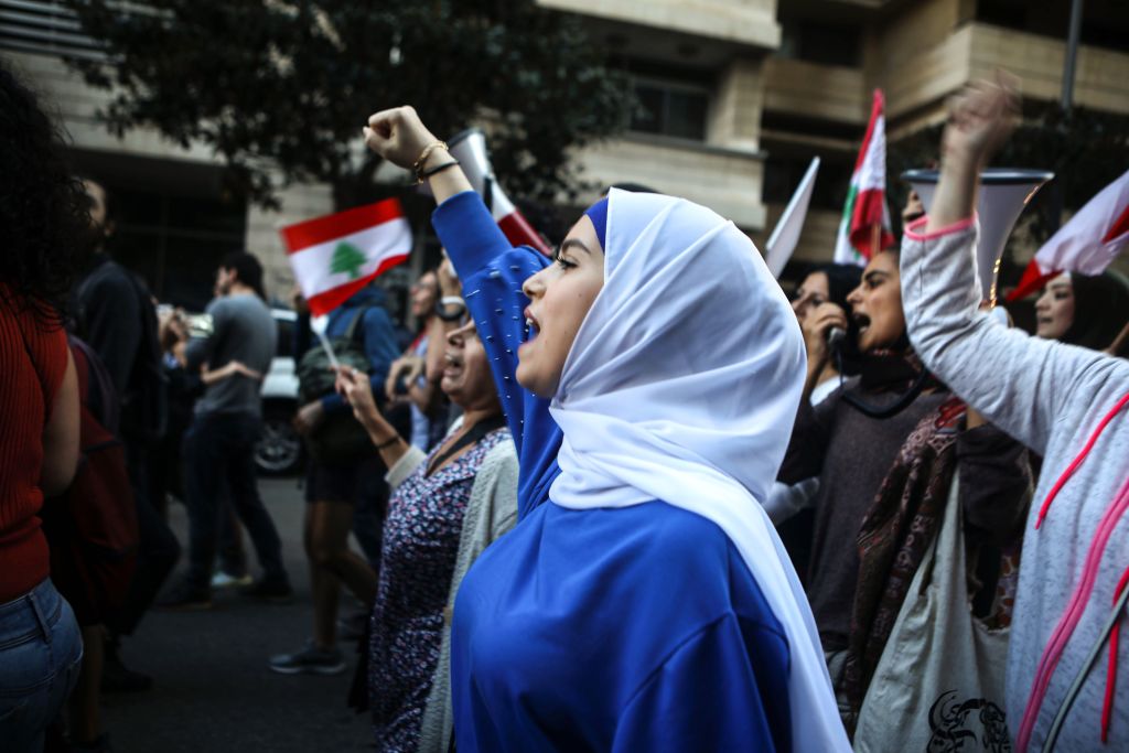 Lebanese anti-government protesters shout slogans as they march on the former demarcation line separating Beirut on December 1, 2019. 