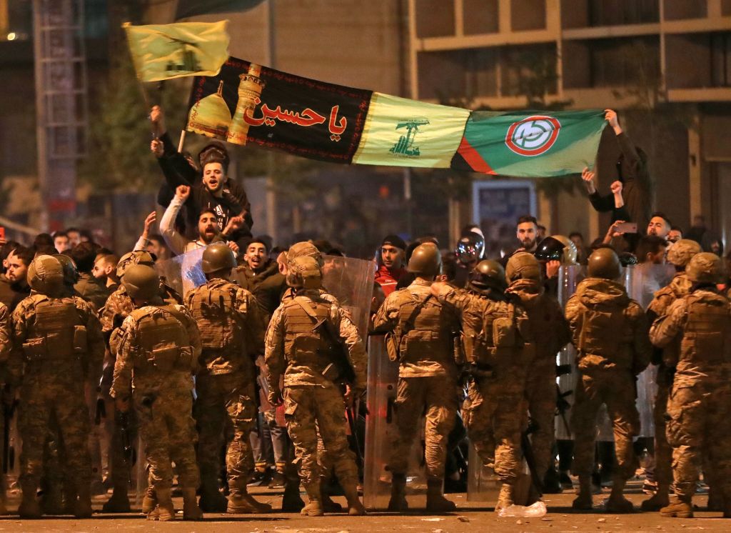 Supporters of Lebanese Shiite groups Hezbollah and Amal wave flags and chant in front of army soldiers in the capital Beirut, on November 25, 2019.