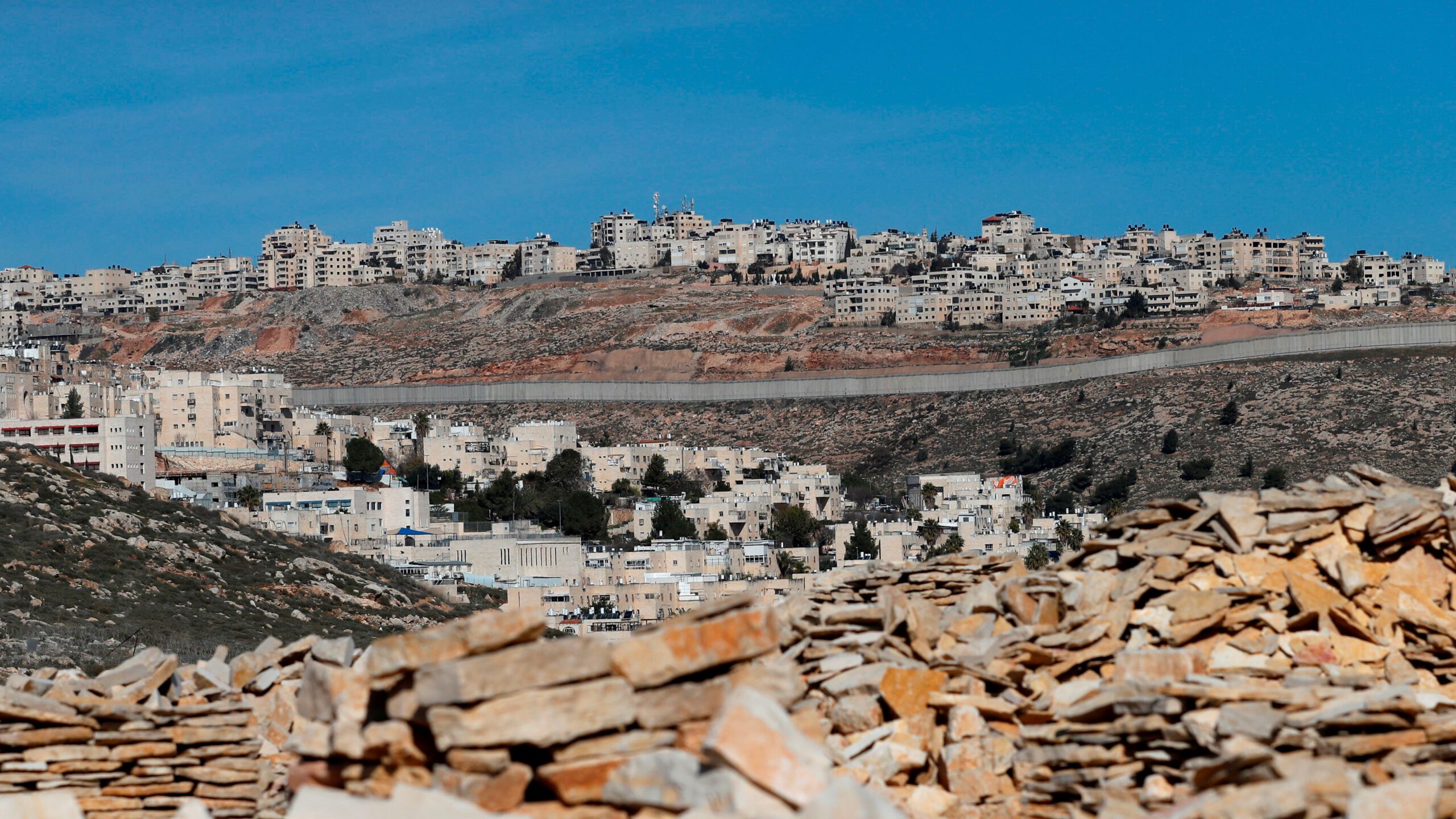 A picture taken on January 27, 2020 shows Israel's controversial concrete barrier (C) separating the Jewish settlement of Neve Yaakov (foreground) in the northern part of east Jerusalem and the Palestinian area of al-Ram (background) in the occupied West Bank. 