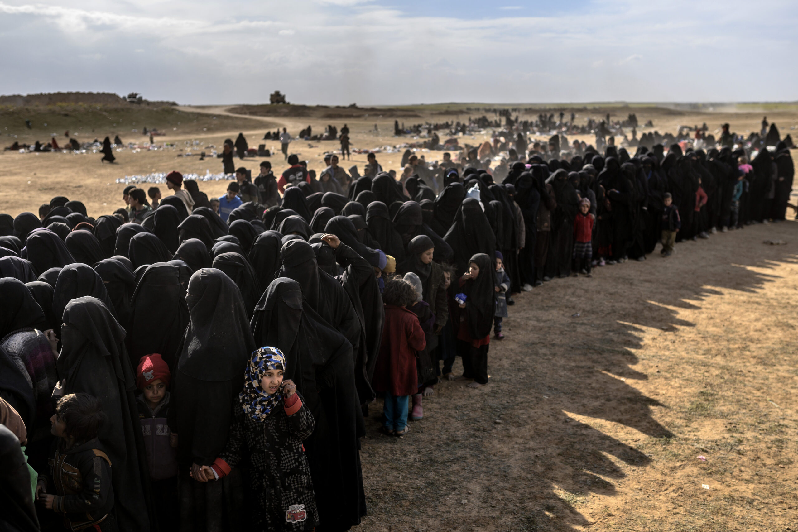 Civilians evacuated from the Islamic State (IS) group's embattled holdout of Baghouz wait for bread and water at a screening area held by the Kurdish-led Syrian Democratic Forces (SDF), in the eastern Syrian province of Deir Ezzor, on March 5, 2019. - More than 7,000 people, mostly women and children, have fled the shrinking pocket over the past two days, as US-backed forces press ahead with an offensive to crush holdout jihadists. (Photo by Bulent KILIC / AFP) (Photo credit should read BULENT KILIC/AFP via