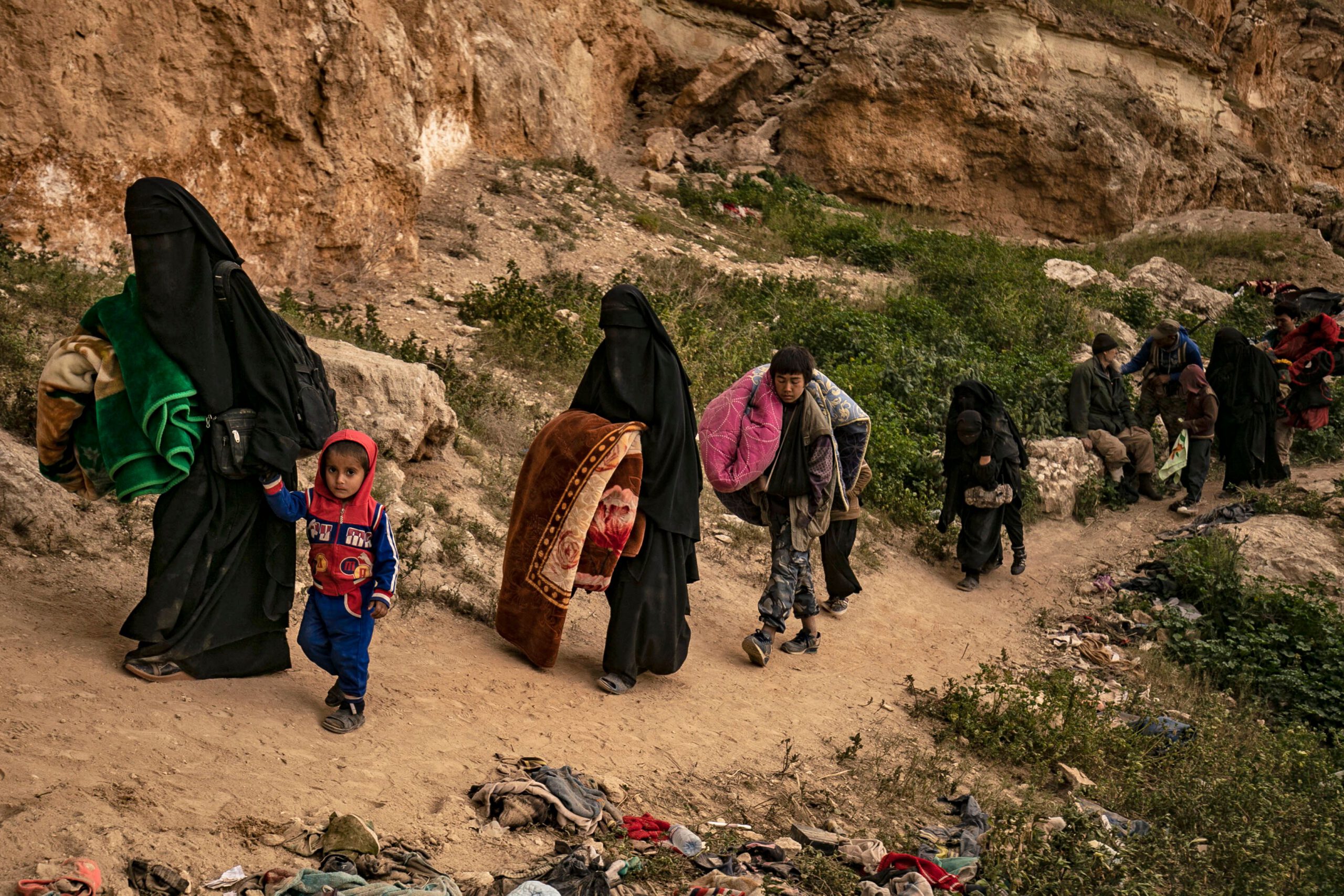 Women wearing full face veils (niqab) walk with children alongside others said to be members of the Islamic State (IS) group by the US-backed Syrian Democratic Forces (SDF), exiting from the village of Baghouz in the eastern Syrian province of Deir Ezzor, on March 14, 2019. (Photo by Delil souleiman / AFP) (Photo credit should read DELIL SOULEIMAN/AFP via Getty Images)
