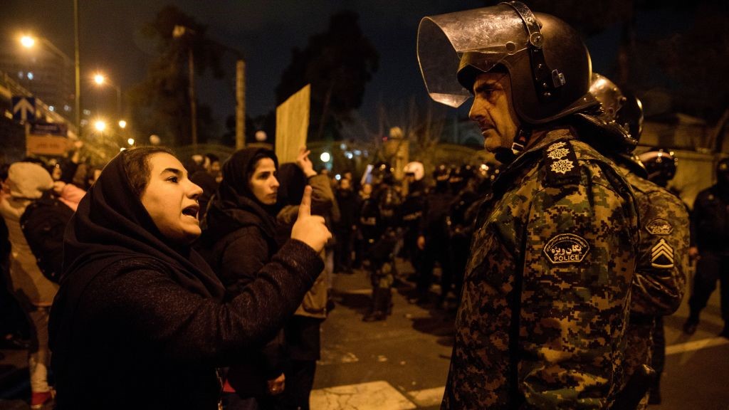 A woman attending a candlelight vigil, in memory of the victims of Ukraine International Airlines Boeing 737, talks to a policeman following the gathering in front of the Amirkabir University in the Iranian capital Tehran on January 11, 2020. 
