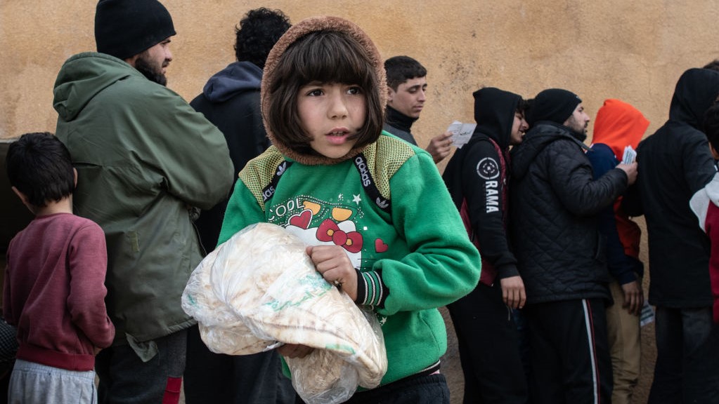  A displaced Syrian girl carries a bag of bread in a stadium which has been turned into a makeshift refugee shelter on February 19, 2020 in Idlib, Syria.