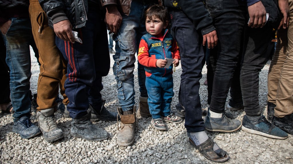 Displaced Syrians wait in a queue as an NGO delivers bread as they wait to receive humanitarian aid in a stadium which has been turned into a makeshift refugee shelter on February 19, 2020 in Idlib, Syria.