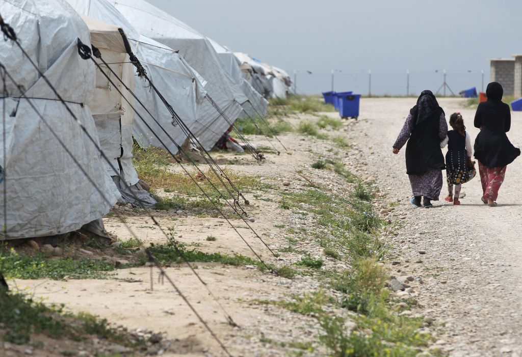 Women and a girl walk outside tents at Laylan camp for the displaced about 25 kilometres east of the northern multi-ethnic Iraqi city of Kirkuk on May 9, 2019.