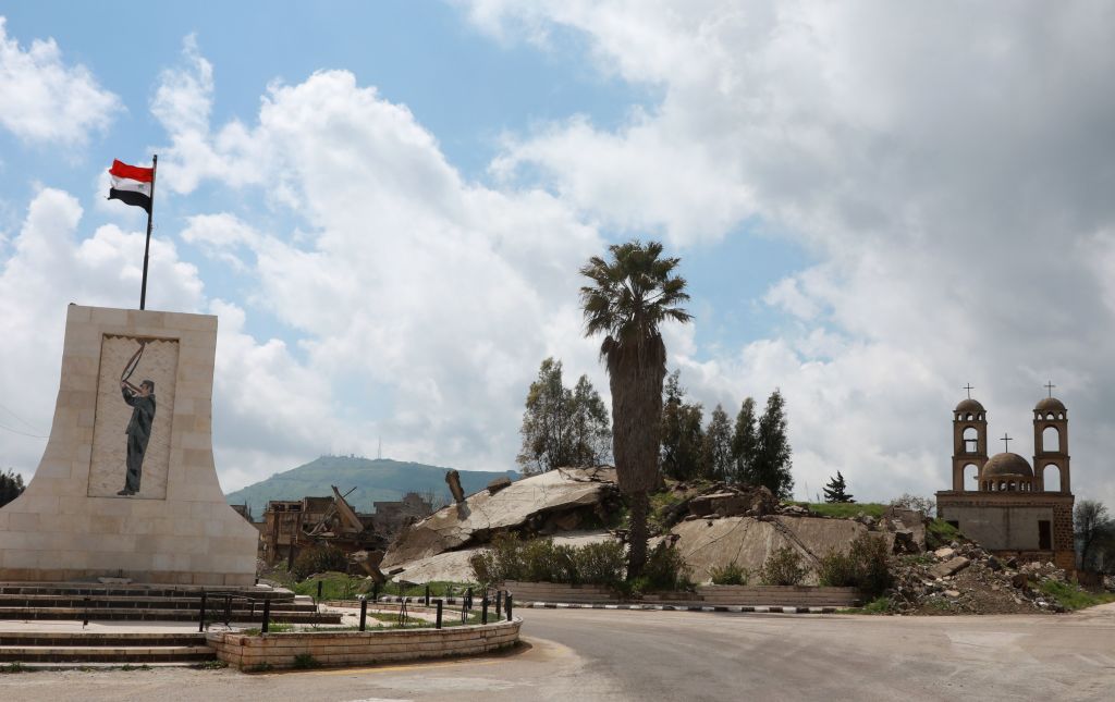 A monument showing an image of the late Syrian president Hafez al-Assad, stands across from a church in the Syrian town of Quneitra in the Golan Heights on March 26, 2019. - US President Donald Trump broke with decades of US policy, signing a proclamation recognising Israeli sovereignty over the strategic territory it seized from Syria in the Six-Day War of 1967 and later annexed in a move never recognised by the international community. (Photo by Louai Beshara / AFP) (Photo credit should read LOUAI BESHARA