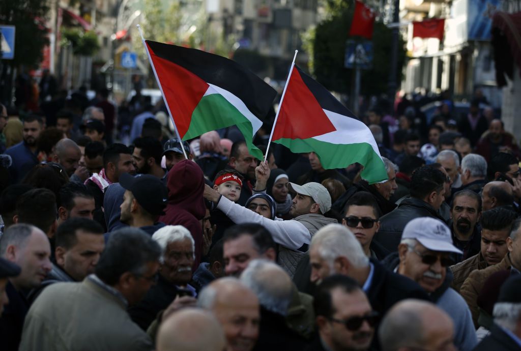 Palestinians wave national flags as they march in the streets of the occupied West Bank city of Ramallah, calling for the cessation of divisions between Fatah and Hamas and the unification of the West Bank and Gaza Strip, on January 12, 2019.