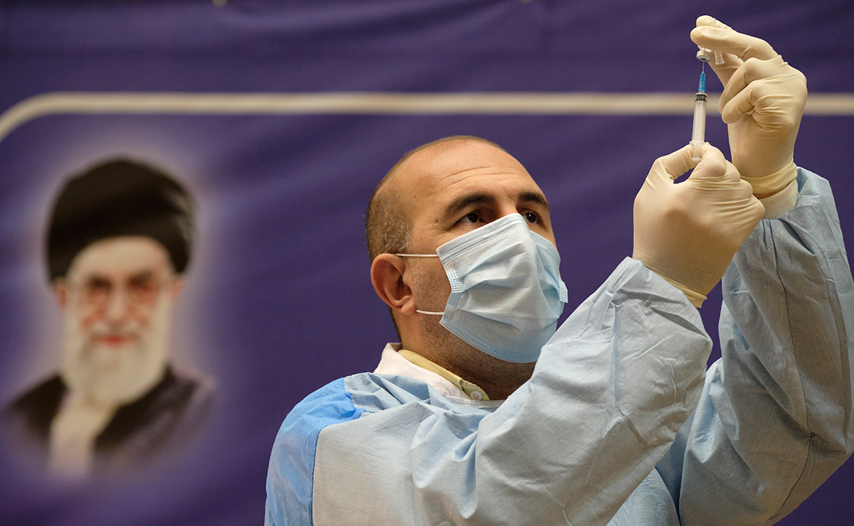 An Iranian medical personnel fills a syringe with the Russian Sputnik-V vaccine, The first registered vaccine against COVID-19, while standing next to a portrait of Irans Supreme Leader Ayatollah Ali Khamenei during a ceremony of initiation of general vaccination against the new coronavirus disease, in a hospital in western Tehran on February 9, 2021. (Photo by Morteza Nikoubazl/NurPhoto via Getty Images)