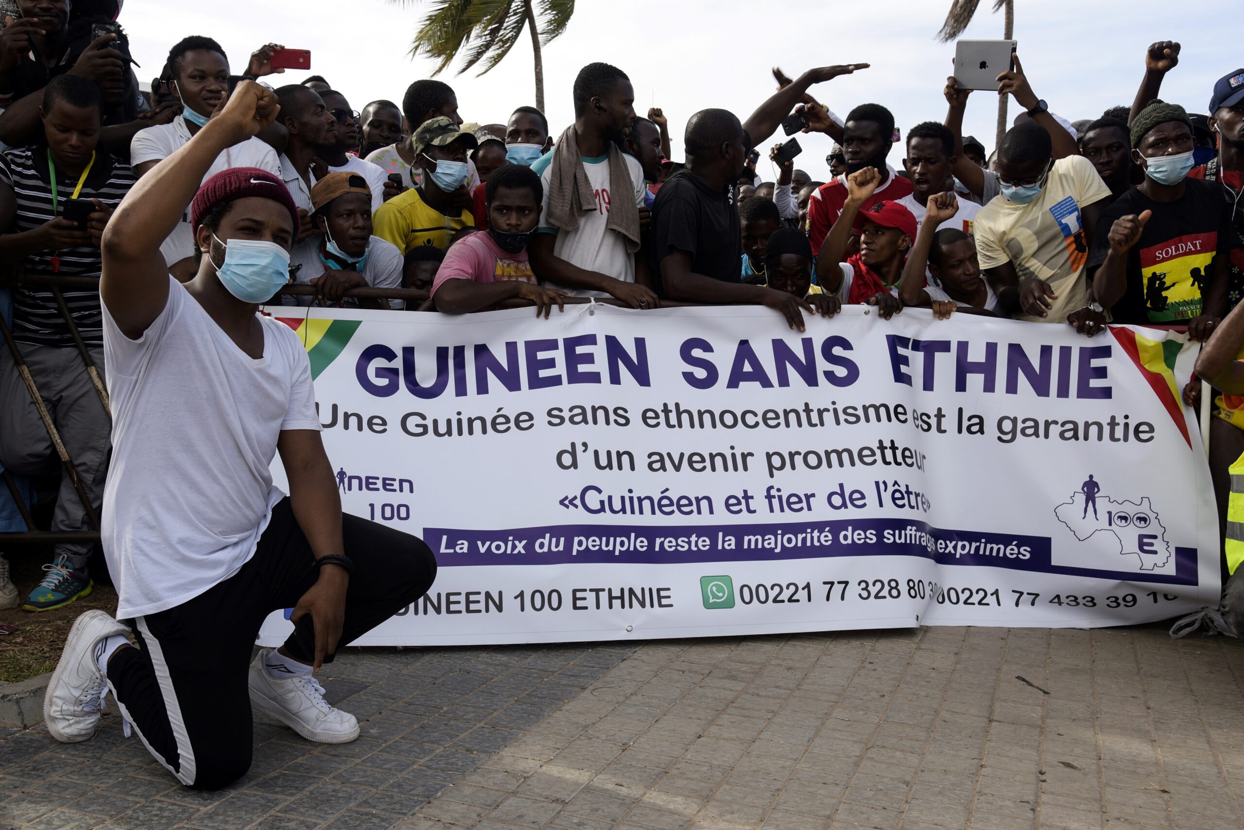 Photo above: Supporters of Guinea’s opposition leader gesture and chants slogans next to a banner reading “Guinea without ethnic groups” as they take part in a gathering in the streets of Dakar, on Oct. 30, 2020, called by the Guinean diaspora to protest against the results of the presidential elections. Photo by FAYEZ NURELDINE/AFP via Getty Images.