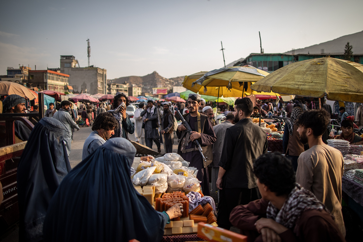 A Taliban fighter stands amid shoppers at a market in Kabul in September 2021. Photo by Oliver Weiken/picture alliancevia Getty Images.