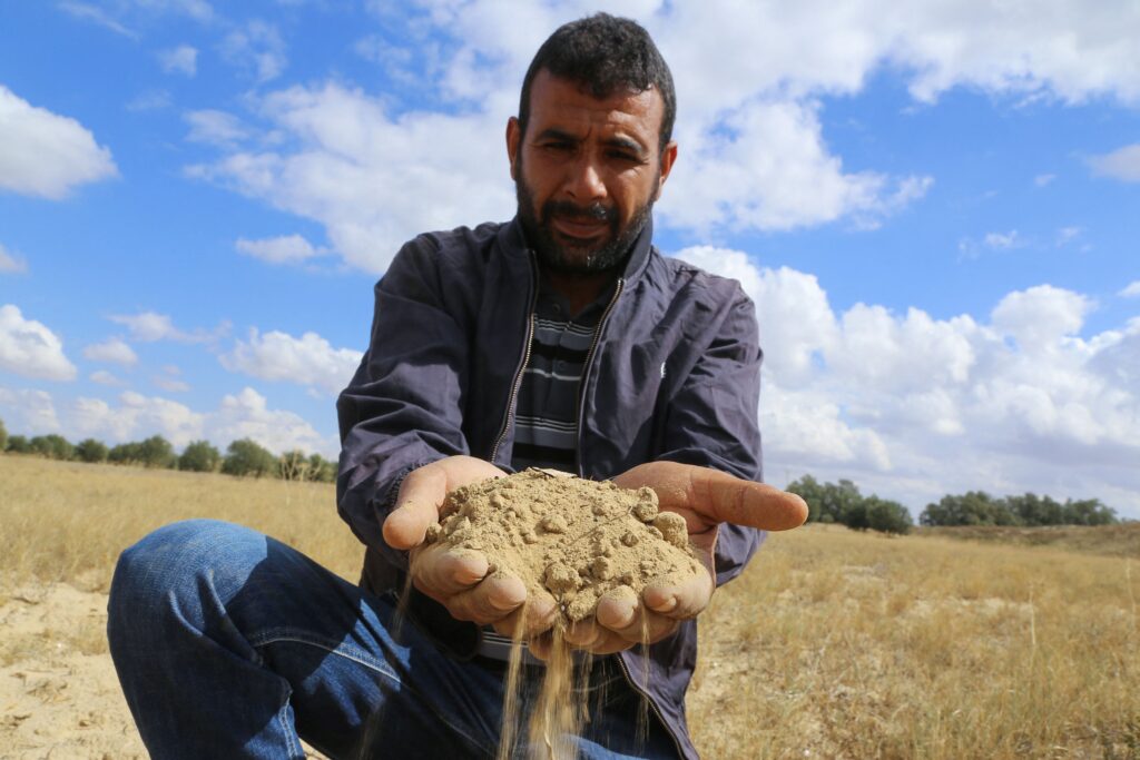 A farmer holds a handful of soil parched because of drought in Tunisia’s east-central area of Kairouan, on Oct. 20, 2021. Photo by Anis Mili/AFP via Getty Images.