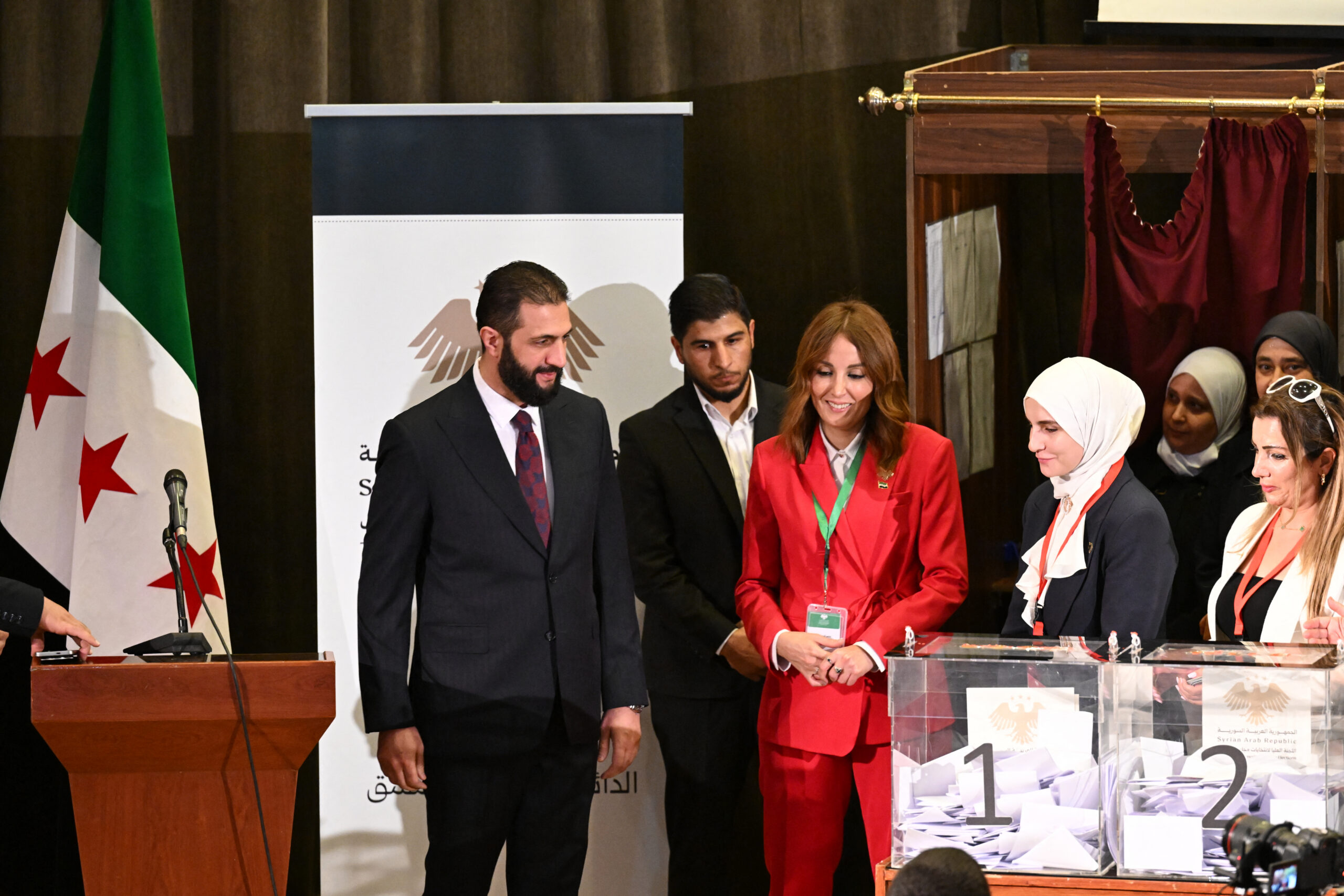 Photo above: Syria’s interim President Ahmed al-Sharaa (L) visits the polling station where members of Syrian local committees have been casting votes to select an interim parliament, October 5, 2025. Photo by Louia Beshara/AFP via Getty Images.