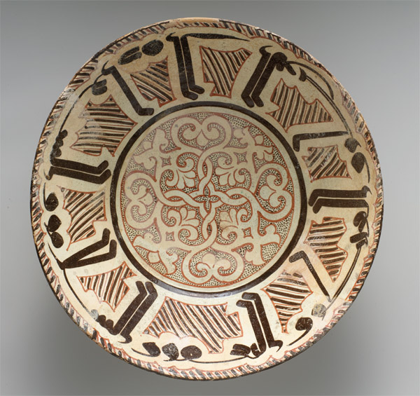 Decorative ceramic bowl with brown and red geometric and floral patterns on a cream background.