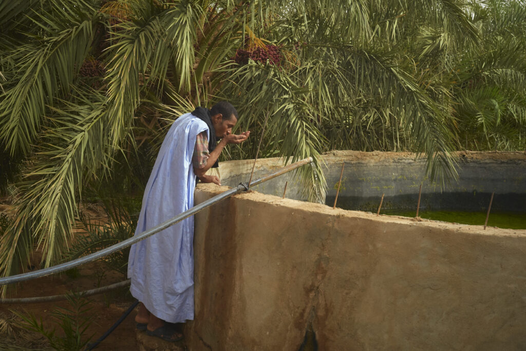 Photo above: A man drinks water from a well in an oasis of date palms in the Adrar region of Mauritania, on June 22, 2024. Source: Michele Cattani/AFP via Getty Images.