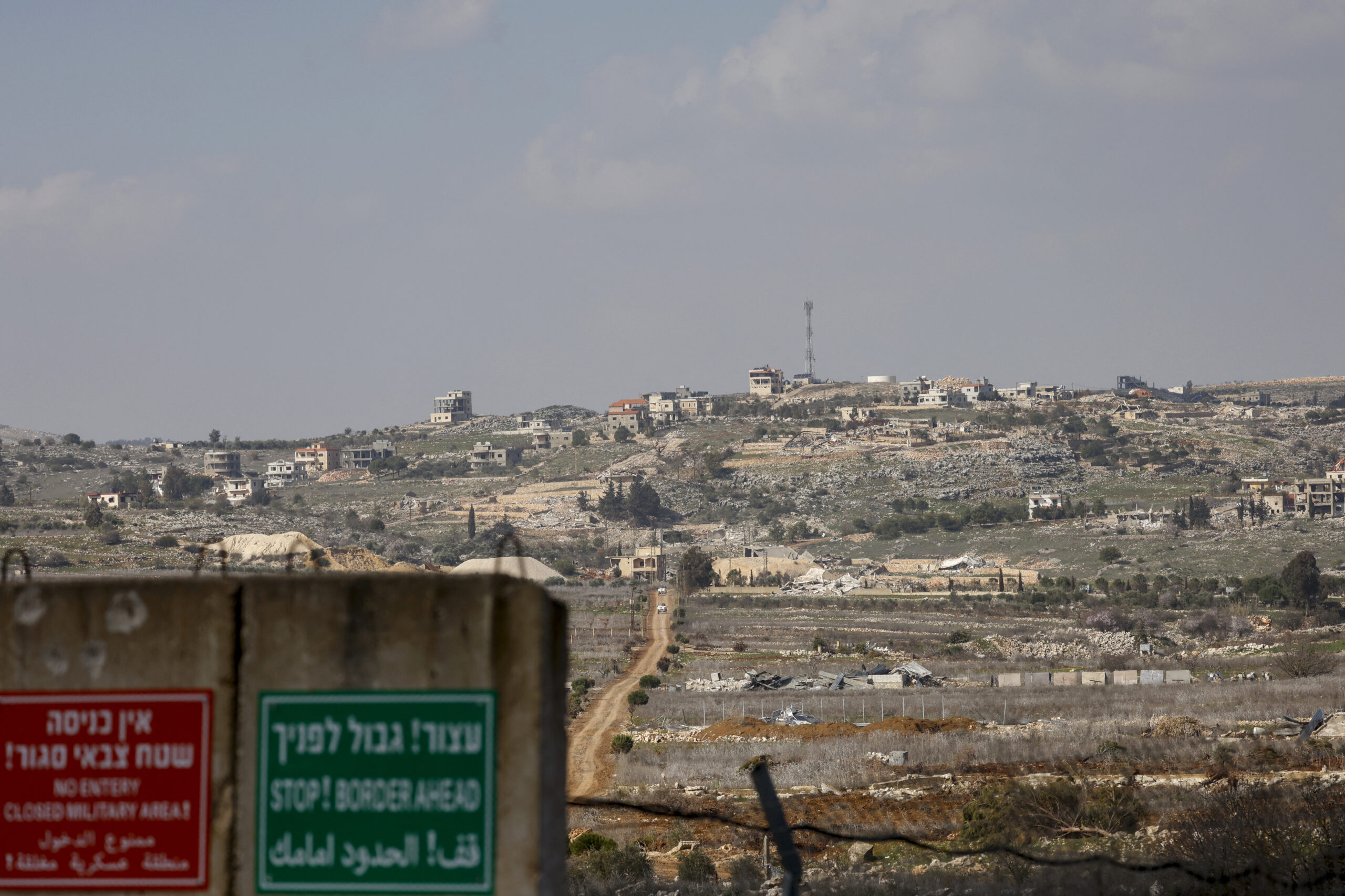 An Israeli military sign sits on the Israel-Lebanon border backdropped by the Lebanese village of Blida, on February 17, 2025. Photo by Jalaa Marey/AFP via Getty Images.